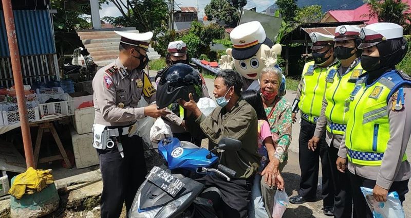 Personil Satlantas Polres Tana Toraja (Tator) membagikan helm bagi pengendara roda dua yang sudah diatas 40 tahun dan yang tertib